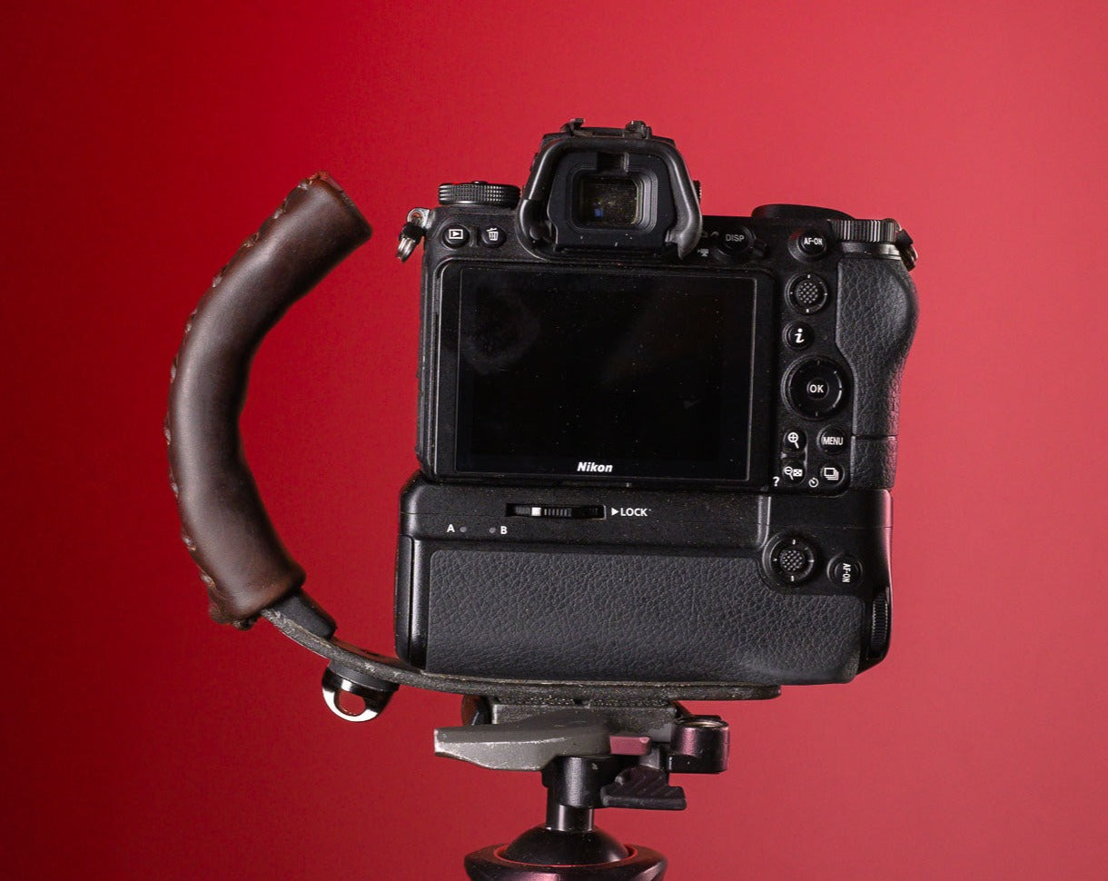 Brown Leather Camera Handle on Mirrorless Camera with a grip attached mounted to a tripod 