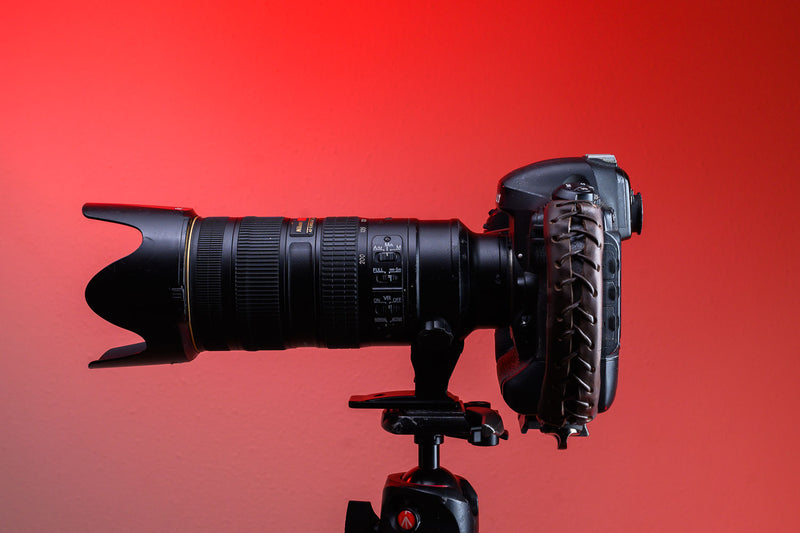 Brown Leather Camera Handle on DSLR Camera with a grip attached mounted to a tripod with a large zoom lens attached