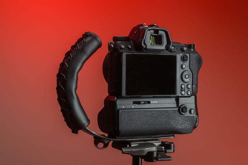 Black Leather Camera Handle on Mirrorless Camera with a grip attached mounted to a tripod 