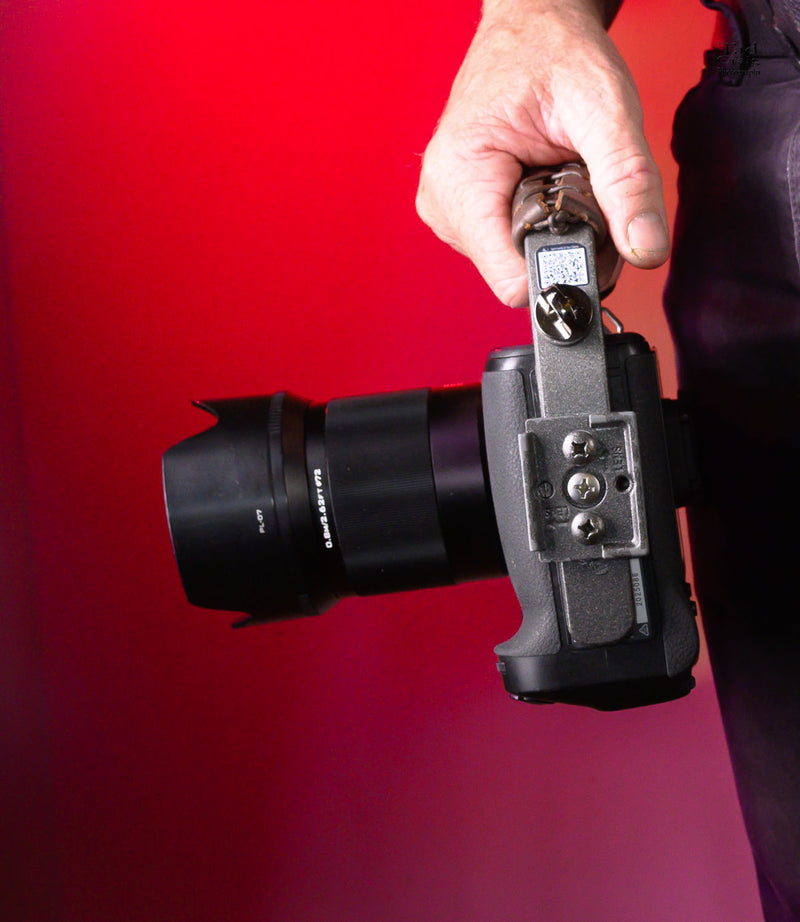 Hand Holding Camera Handle attached to a mirrorless camera w a tripod plate showing
